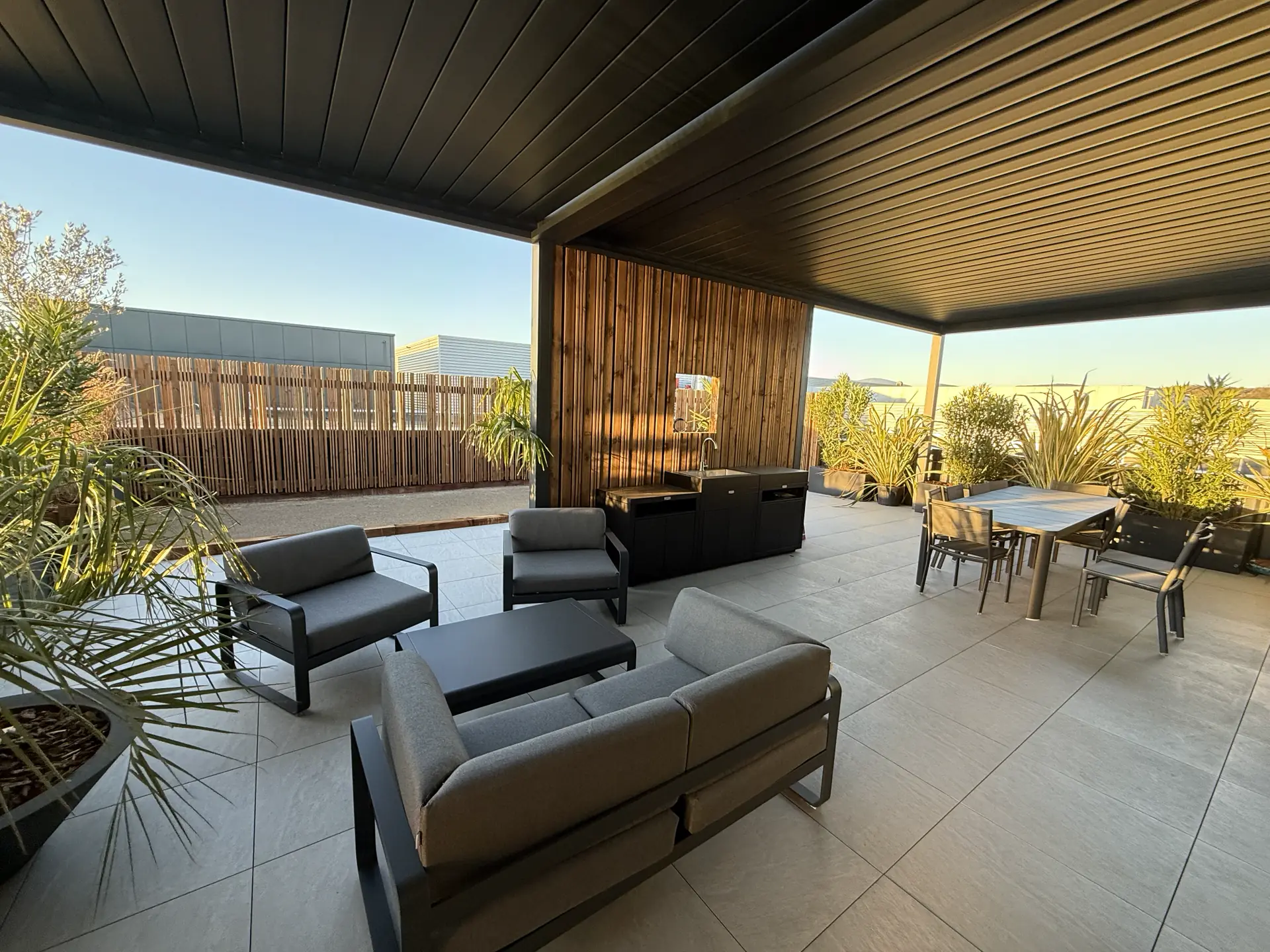 Terrasse d'entreprise sous pergola avec canapés et table extérieure à Reventin-Vaugris