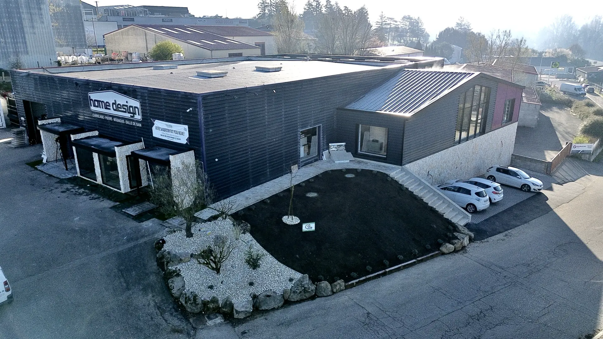 Vue aérienne d'un showroom à bardage noir et de son parking à Estrablin, près de Vienne