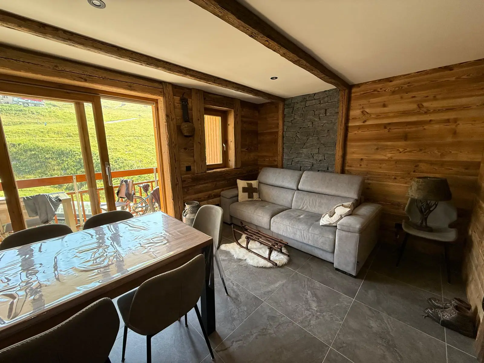Pièce de vie d'un chalet rénové avec murs en bois vieilli et vue sur la montagne