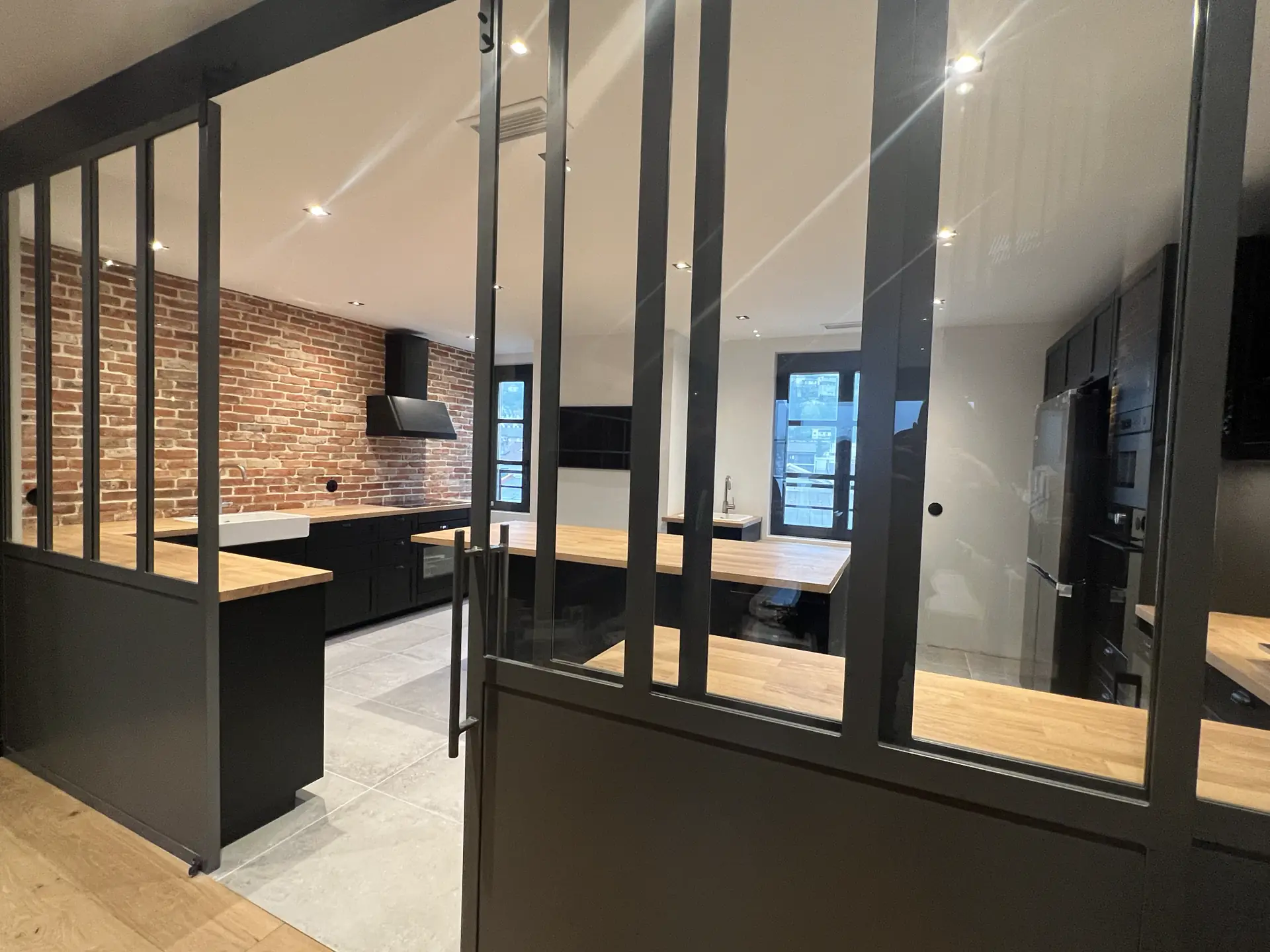 Verrière noire de style atelier ouvrant sur une cuisine rénovée à Vienne