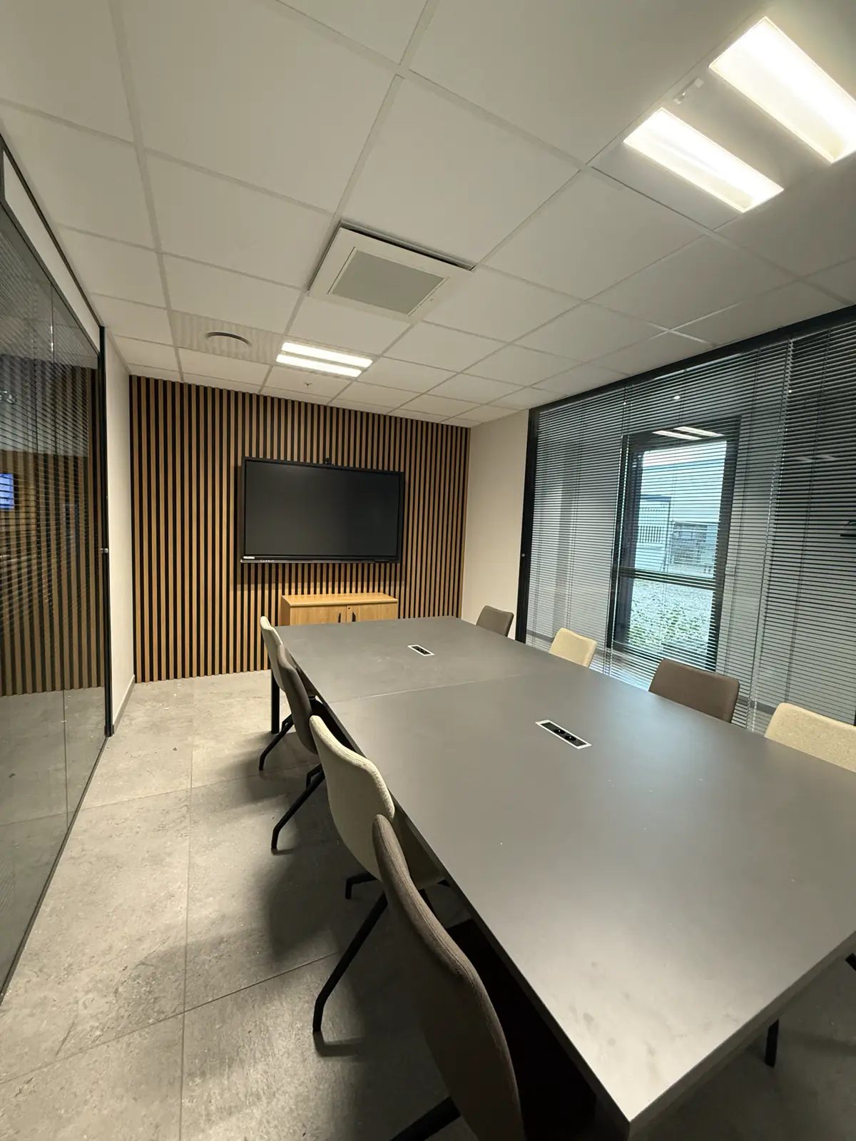Salle de réunion avec grande table et écran dans des bureaux à Reventin-Vaugris